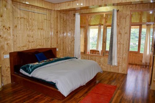 a bedroom with a bed with wooden walls and windows at Keylong villa in Kyelang
