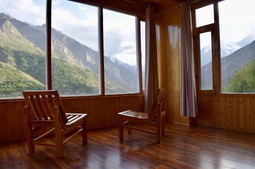 two chairs in a room with a view of mountains at Keylong villa in Kyelang