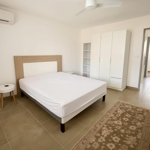 a bedroom with a large white bed and a rug at Appartement cosy - extérieur et parking in La Trinité