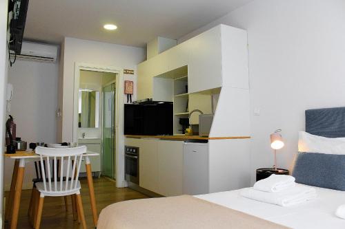 a bedroom with a bed and a kitchen with a table at Apartamentos do Corgo in Vila Real