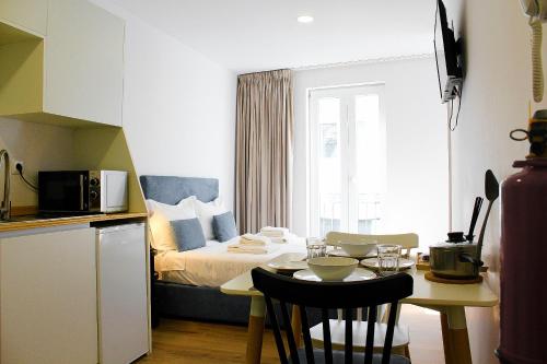 a room with a bed and a table and a kitchen at Apartamentos do Corgo in Vila Real