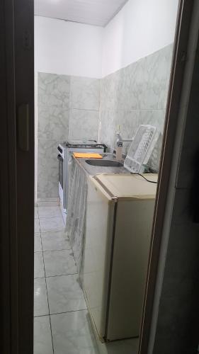 a small kitchen with a sink and a stove at Kitnet temporada mobiliada Beira Mar in Rio das Ostras