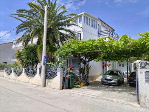a car parked in front of a house with a palm tree at Apartmani Punta in Zadar