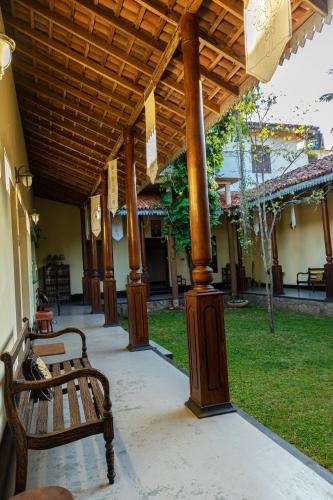 a porch with two benches under a wooden pergola at Illukawela Walauwa in Embilipitiya