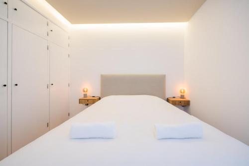 Un dormitorio blanco con una gran cama blanca con dos lámparas. en Cascais Apartment, en Cascais