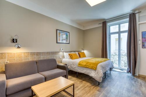 a living room with a couch and a bed at Hôtel Mistral Comédie Saint Roch in Montpellier