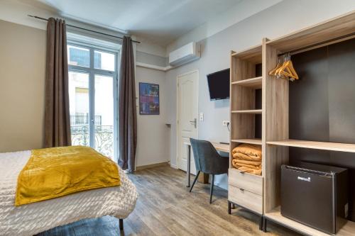 a bedroom with a bed and a desk and a window at Hôtel Mistral Comédie Saint Roch in Montpellier