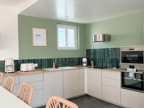 une cuisine avec des armoires blanches et des murs verts dans l'établissement Villa Rompsay, à La Rochelle