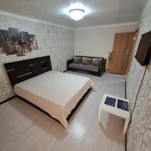 Un dormitorio con una cama grande y un sofá. en Квартиры, en Shchūchīnsk