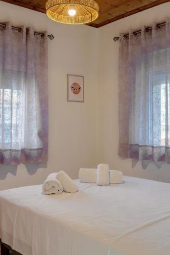 a bedroom with a bed with white sheets and windows at Alex Apartments in Preveza