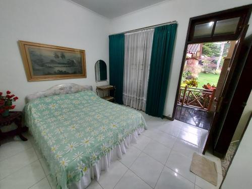 a bedroom with a bed with a green blanket and a window at Villa Kusuma 14, Large Garden & Karaoke in Batu City in Batu