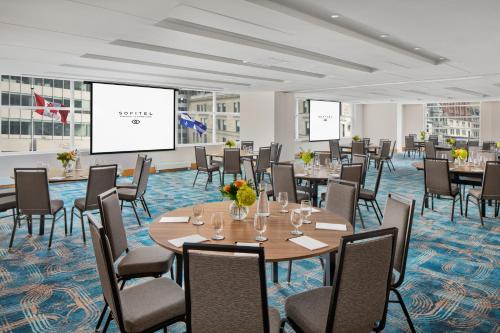 a conference room with tables and chairs and a projection screen at Sofitel Montreal Golden Mile in Montréal