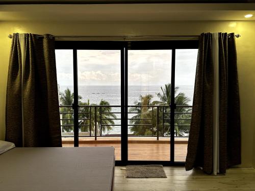 a bedroom with a large window with a view of the ocean at Exclusive Beachfront House with Pool Batangas 16pax in Lobo