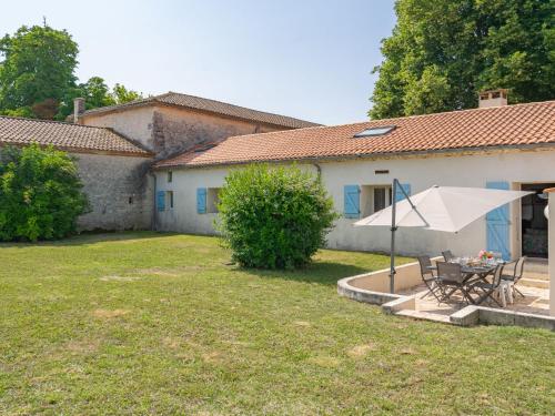 a house with a table and a umbrella in the yard at Holiday Home Château de Taupignac by Interhome in Breuillet