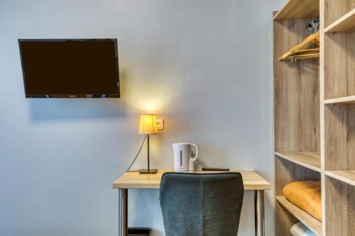 a desk with a chair and a tv on a wall at Hôtel Mistral Comédie Saint Roch in Montpellier