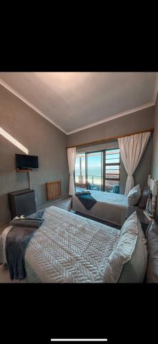 a bedroom with two beds and a large window at Lilies & Leopards B&B in Mossel Bay