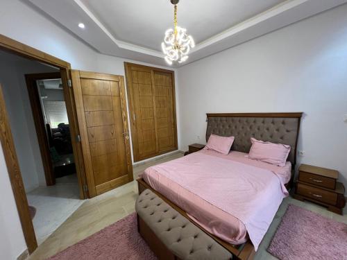 a bedroom with a bed with pink sheets and a chandelier at Luxury Apartment in Nabeul