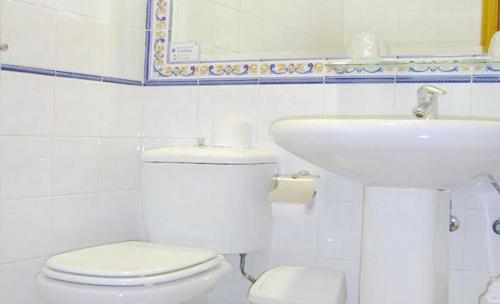 a white bathroom with a toilet and a sink at Hotel Miraflores in Alcobendas