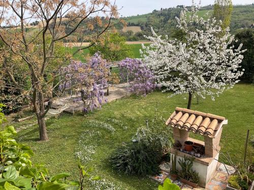 a garden with a dog house and a flowering tree at Casa Rossa in Montecassiano