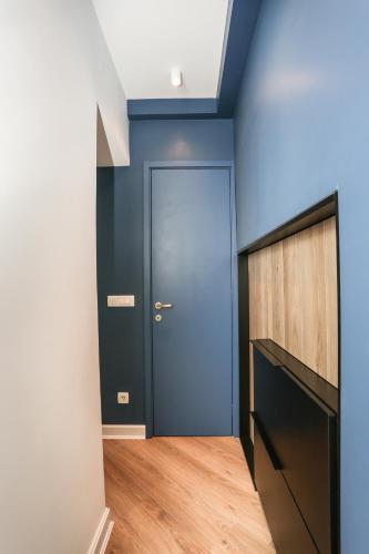 a hallway with a blue door and a wooden floor at Moment Boutique Apartments in Belgrade