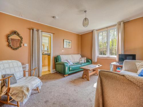 a living room with a green couch and a tv at Chalet Rowan Chalet by Interhome in Inverness