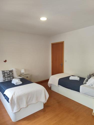 two beds in a bedroom with white walls and wood floors at Portus Ribeira House in Vila Nova de Gaia