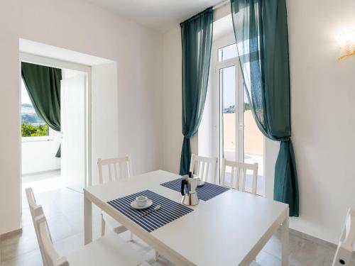 un comedor con una mesa blanca y cortinas verdes en Apartment Galatea by Interhome, en Arma di Taggia