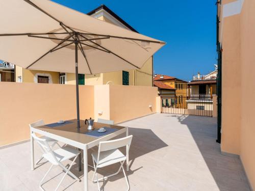Una mesa y sillas con una sombrilla en un patio. en Apartment Galatea by Interhome, en Arma di Taggia