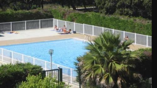 une grande piscine avec des personnes assises autour de celle-ci dans l'établissement Duplex T3 facing Coudoulière Beach, à Six-Fours-les-Plages