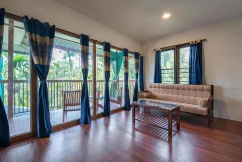 a living room with a couch and some windows at GreensVista Wayanad AC Pillar Homestay near Natural Stream and Amazing View in Panamaram