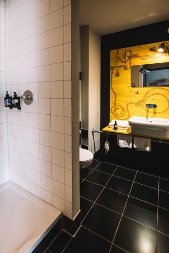 a bathroom with a sink and a tub and a mirror at Superbude Hamburg St Pauli in Hamburg