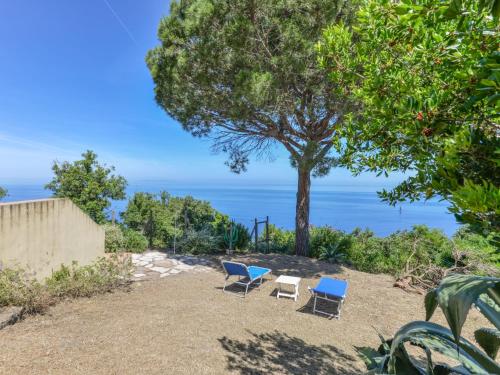 two chairs and a tree with the ocean in the background at Holiday Home L'Aietta di Maciarello by Interhome in SantʼAndrea