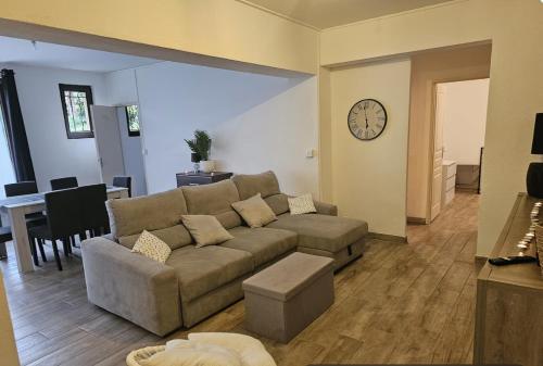 un salon avec un canapé et une horloge au mur dans l'établissement Grand appartement proche centre ville, à Digne-Les-Bains