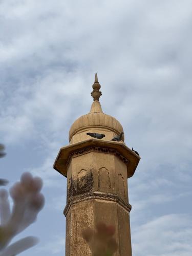 a clock tower with a sky in the background at Mandawa Kothi in Mandāwa