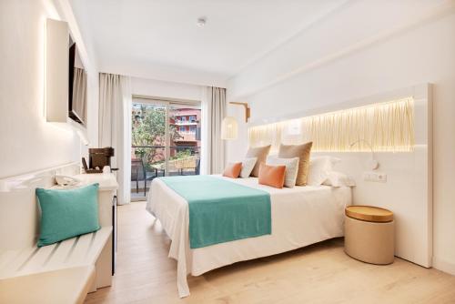 a white bedroom with a bed and a window at Hotel Ipanema Beach in El Arenal