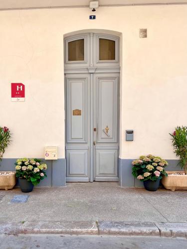a door of a building with two potted plants at Le National Sète Centre Gare,Ascenseur in Sète