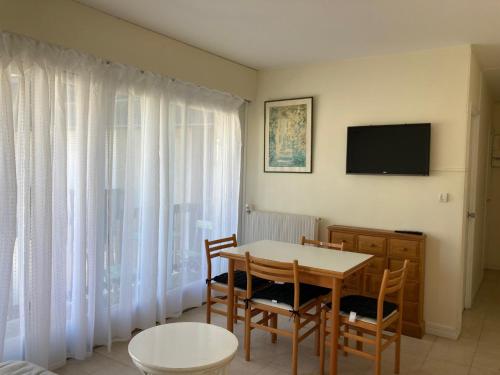 une salle à manger avec une table, des chaises et une télévision dans l'établissement Beau 2P à Deauville avec balcon, à La Celle-sous-Gouzon