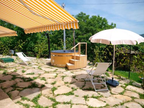 un patio con bañera de hidromasaje y sombrilla en Holiday Home Poderi Alugi Serravalle by Interhome, en Piasco