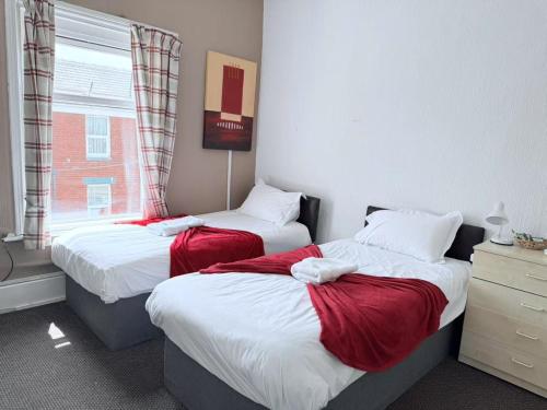 a bedroom with two beds with red sheets and a window at The Aberford in Blackpool