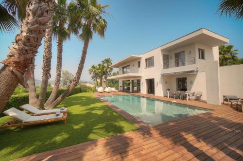 une maison avec une piscine et des palmiers dans l'établissement FRGK Luxury Villa Cannes Croix des Gardes, à Cannes