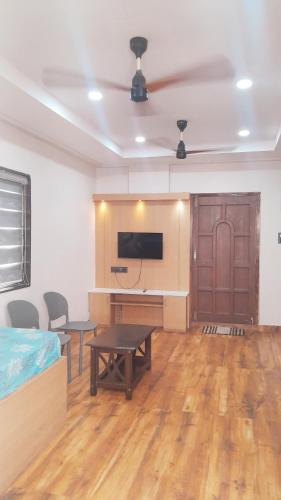 a room with a bed and a desk and a tv at Vizag Venya Vihar a 2BHK Deluxe Furnished HomeStays in Visakhapatnam