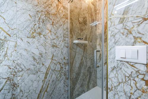 a bathroom with a shower with a marble wall at Prestige Suite Via Romagnoli in Sirmione