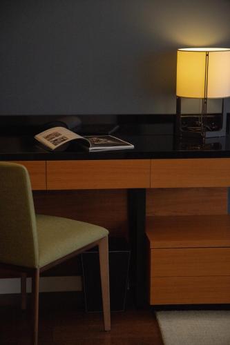 a desk with a lamp and a book and a chair at Fraser Suites Geneva - Serviced Apartments in Geneva