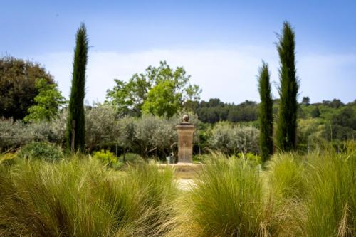 a monument in a garden with tall grass and trees at Mas des Cèdres in Ménerbes
