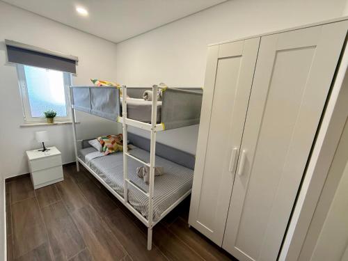 a small room with bunk beds and a window at Tomasoni summer house in Armação de Pêra