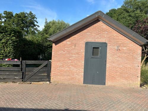 a brick building with a door and a fence at Zonneoord in Ede