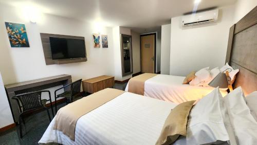 a hotel room with two beds and a flat screen tv at Hotel BE Suites Cali in Cali