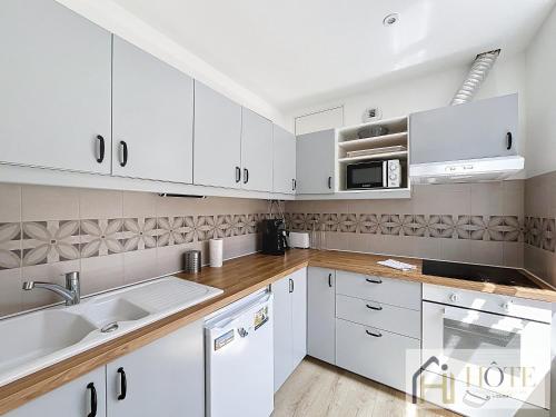 une cuisine avec des armoires blanches et un évier dans l'établissement Spacieux 1 Chambres avec Terrasse, 50m de la Plage, à Dunkerque