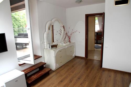 a white bathroom with a mirror and a dresser at Pensjonat E&M in Mikołajki