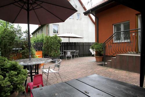 an outdoor patio with tables and chairs and an umbrella at Pensjonat E&M in Mikołajki
